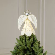 a christmas tree with a white angel decoration hanging from it's top and green branches