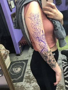 a woman is taking a selfie in the mirror with her phone and flowers on her arm