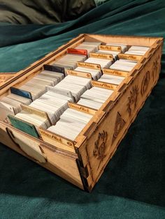 a wooden box filled with lots of cards on top of a green cloth covered bed