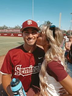 a man and woman kissing each other at a baseball game