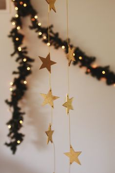 some gold stars hanging from the ceiling in front of a christmas tree with lights on it