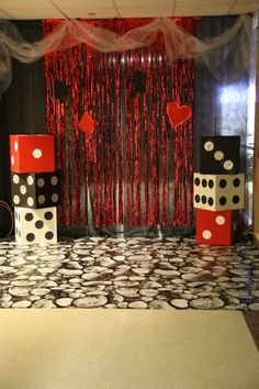 some black and white polka dot boxes are on the floor in front of a red curtain