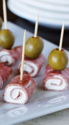 several appetizers are arranged on a plate with toothpicks and olives