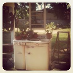 an old fashioned stove and sink outside in the yard with potted plants on it