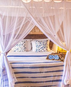 a bed with white drapes and blue pillows