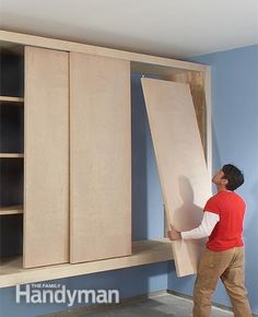 a man standing next to a cabinet with the door open and another person holding it up