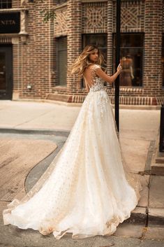 a woman in a wedding dress leaning against a pole