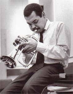 a man sitting down playing a trumpet