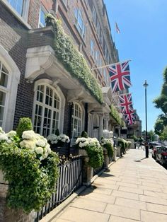 the british flag is hanging on the side of this building with white flowers and greenery