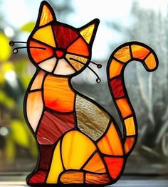 a stained glass cat sitting on top of a window sill