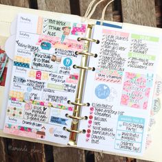 an open planner book with lots of stickers and writing on the pages, sitting on top of a wooden table