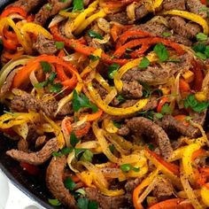 a skillet filled with meat, peppers and onions