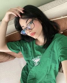 a woman wearing glasses laying on top of a bed