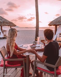 two people sitting at a table on the beach