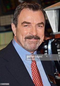 a man in a suit and tie smiles at the camera while standing next to a machine