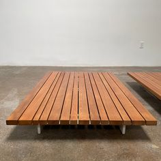 two wooden benches sitting next to each other in a room with concrete flooring and white walls