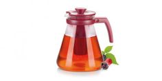 a red glass tea pot filled with liquid and berries on the side next to it