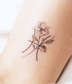 a small flower tattoo on the side of a woman's leg, with black ink