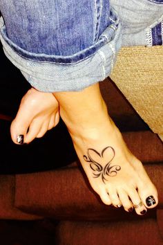 a woman's foot with a butterfly tattoo on her left side and black dots in the middle