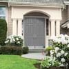 a house with flowers in the front yard and bushes on the side walk to the front door