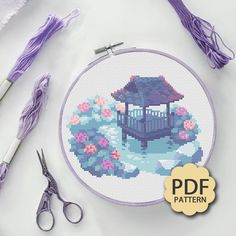 a cross stitch pattern with scissors, yarn and thread on the table next to it