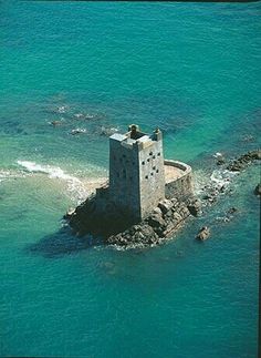 an aerial view of a tower in the middle of the ocean with water around it