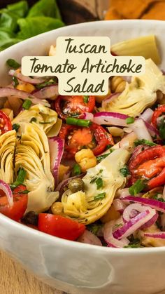 a white bowl filled with pasta salad on top of a wooden table next to lettuce and tomatoes