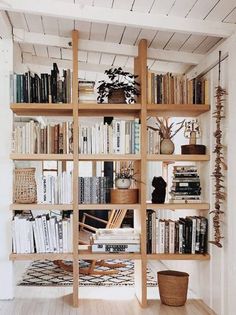 a bookshelf filled with lots of books next to a basket and potted plant