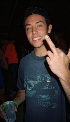 a young man is making the peace sign with his hand while standing in front of other people