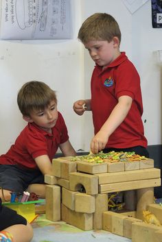 two young boys playing with wooden blocks in a classroom