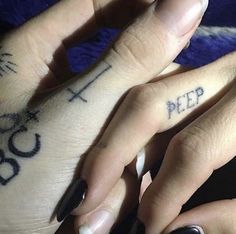 two people with tattoos on their fingers and one has the word pee written on it