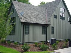 a large gray house sitting on the side of a road next to a lush green forest