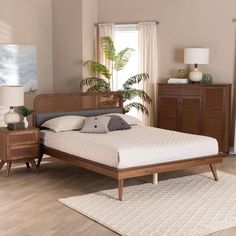 a bed sitting on top of a wooden floor next to a dresser and lamp in a bedroom