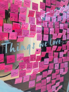 many pink sticky notes are attached to the glass wall in front of a store window