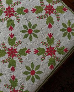 a white quilt with red and green flowers on it