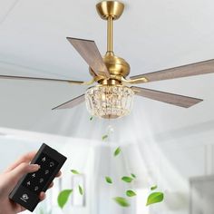 a person holding a remote control in front of a ceiling fan