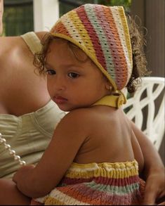 a woman holding a small child in her arms and wearing a crocheted hat