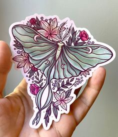 a hand holding a sticker with an image of a butterfly on it's wings