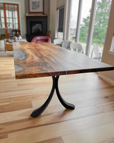 a wooden table sitting on top of a hard wood floor next to a large window