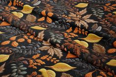 an orange and black fabric with yellow leaves on the top is shown in close up