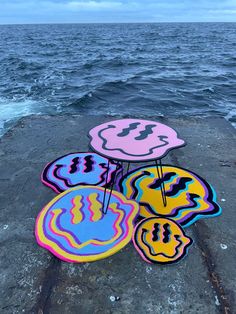 four colorful rugs sitting on top of a rock next to the ocean