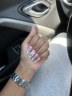 a woman's hand with pink and white nails sitting in the driver's seat of a car