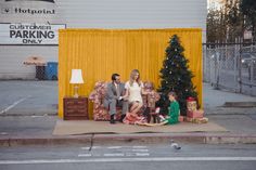 a family sitting on a couch in front of a christmas tree with presents under it