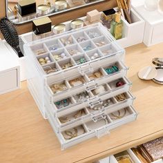 the drawers are filled with jewelry and bracelets in clear plastic containers on a wooden table