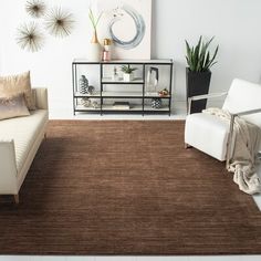 a living room with two white chairs and a brown rug on the floor in front of a couch