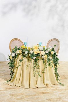 the table is covered with yellow flowers and greenery