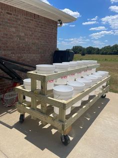 several buckets sitting on top of a cart in front of a brick building