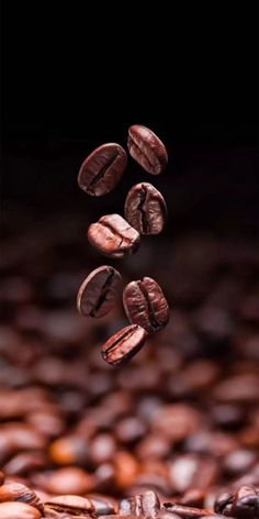 coffee beans falling down into the air on top of some brown and black grounding