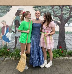 three young women standing next to each other in front of a wall with a mural on it