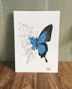 a blue butterfly with geometric shapes on it's wings sits on a wooden surface